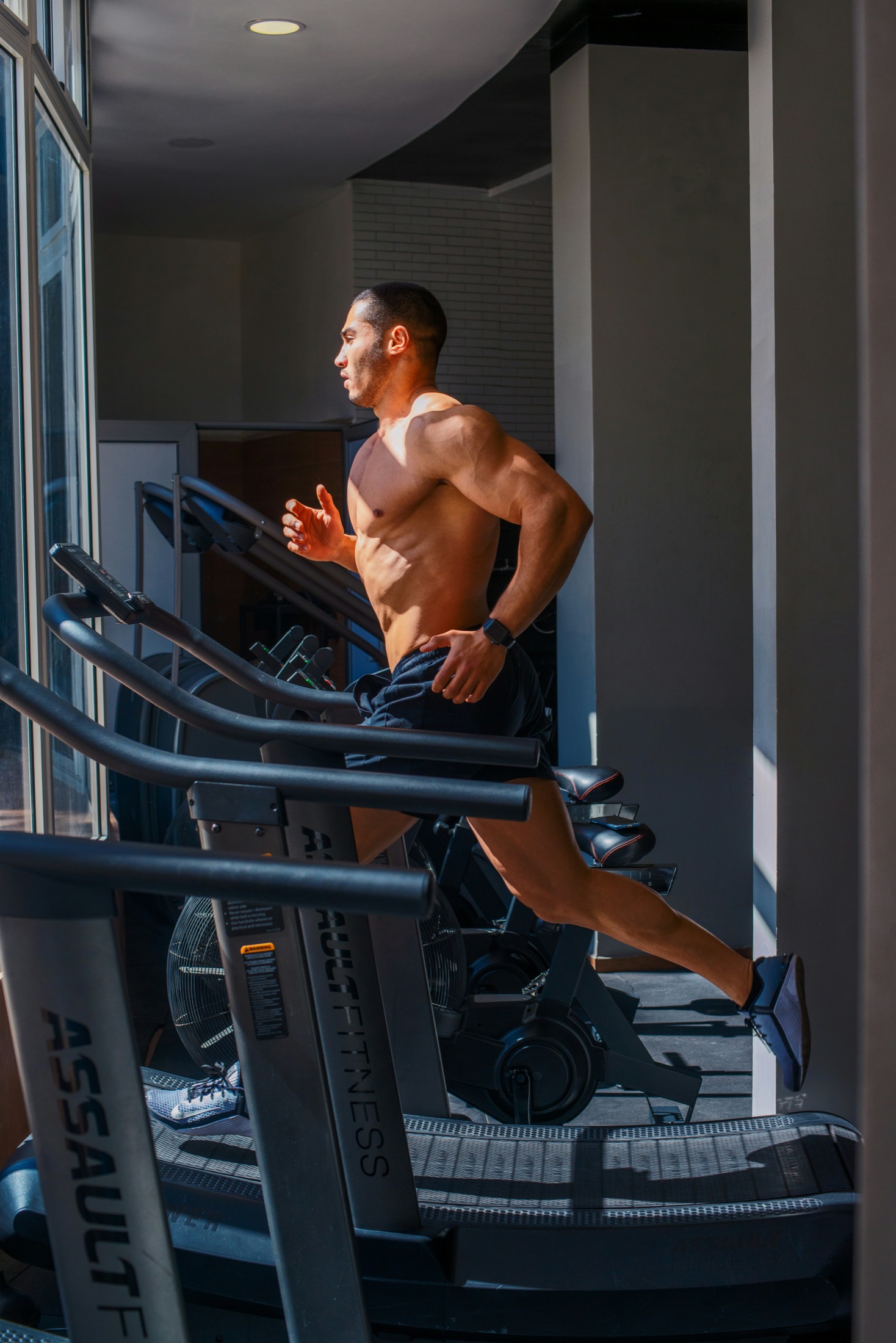 Runner using a curved treadmill in a sunlit gym